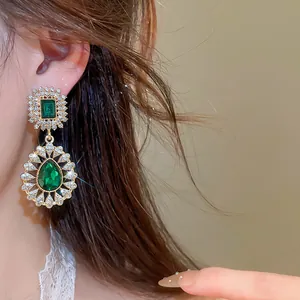 Detail of vintage court style dangle earrings with green emerald gems and rhinestones