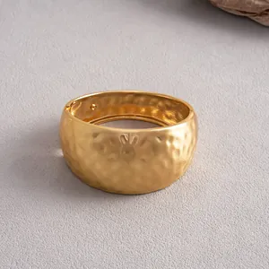 Detailed view of wide hammered gold metal bangle with irregular textured surface