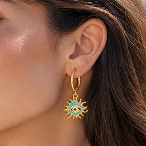 Gros plan détaillé d'une boucle d'oreille œil maléfique en acier inoxidable doré sur un modèle