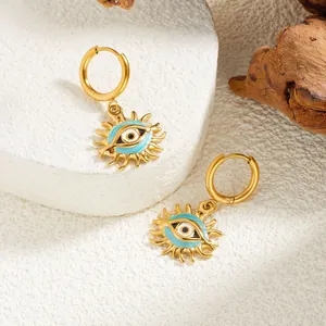 Vue détaillée de boucles d'oreilles créoles soleil mauvais œil en acier doré sur décor