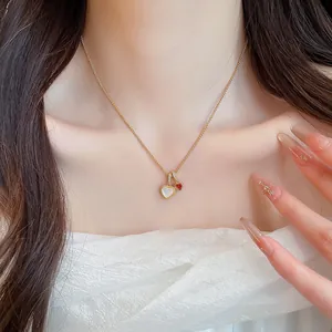 Primo piano di un'elegante collana dorata con ciondoli a cuore in madreperla e zircone