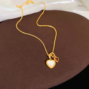 Primo piano collana cuore placcata oro 18k con conchiglia e pietre rosse