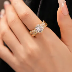 Nahaufnahme eines 18 Karat vergoldeten Rings mit Zirkonia-Halo-Fassung an Hand