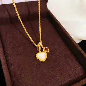 Dettaglio della collana placcata oro 18k con cuore in madreperla bianca e pietra rossa