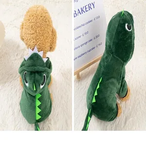 Detailansicht des grünen Plüsch-Dinosaurier-Kostüms für kleine Hunde im Café-Ambiente.