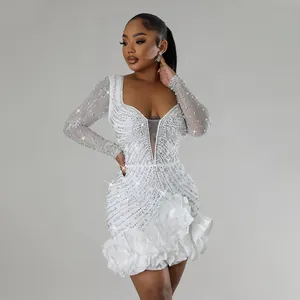 Detailed view of white rhinestone beaded long sleeve mini dress with ruffle hem