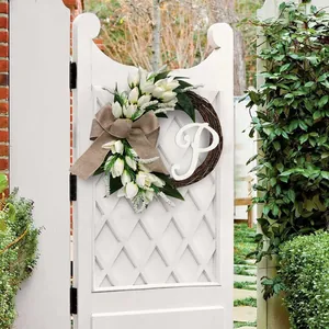 Decorative white tulip wreath featuring letter P and burlap bow on a white garden gate.