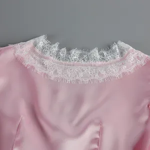 Detailed view of the elegant pink satin dress featuring a delicate white lace neckline trim