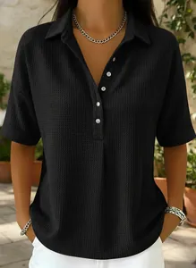 Détail d'un polo noir en maille gaufrée à manches courtes et boutons pour un look décontracté.