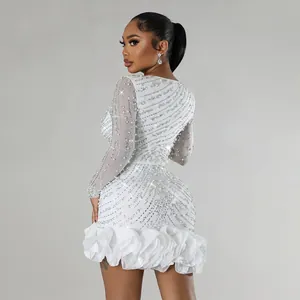 Detailed view of white mini dress featuring intricate pearl and rhinestone embellishments.