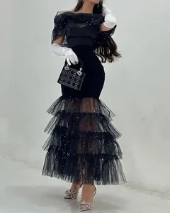 Detalle del vestido de noche de tul negro con capas, lentejuelas y guantes blancos