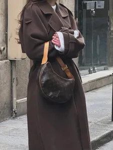 Stylish brown double-breasted long wool overcoat shown in a street fashion detail shot.