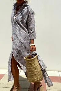 Side view of a bohemian geometric print shirt dress with side slits and a woven basket bag.