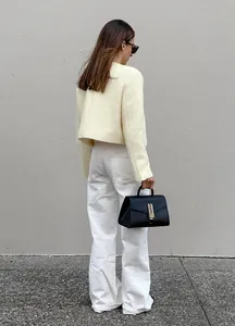 Elegante kurze Tweedjacke in Creme kombiniert mit einer weißen weit geschnittenen Hose.