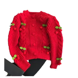 Vibrant red chunky knit cardigan with 3D cherry pom-poms for a sweet autumn look.
