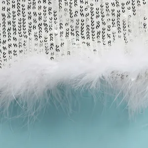 Macro detail of white sequin fabric with elegant fluffy feather trim on a sexy dress.