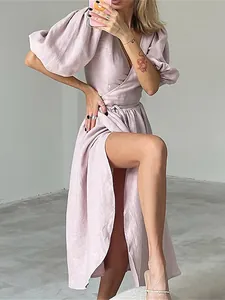 Detail view of a lavender linen wrap dress with puff sleeves and a high leg slit.