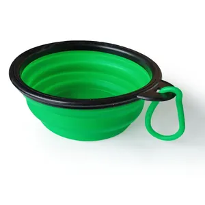 A green collapsible silicone pet bowl shown from the side with its plastic clip