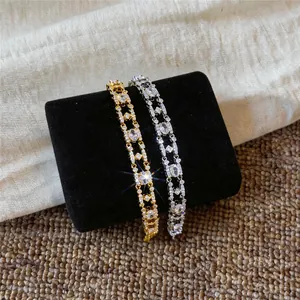 Macro detail of 18k gold plated bracelets with oval zircons on black velvet stand.