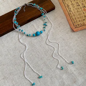Close-up view of bohemian turquoise stone beaded multi-layer fringe necklace on linen