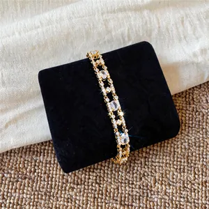Macro detail of 18k gold plated bracelet with sparkling oval zircons on black velvet