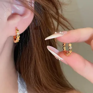 Detailed macro shot of 18k gold-plated zircon hoop earrings worn by a fashion model