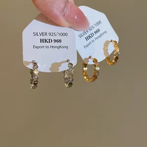 Detailed macro shot of minimalist 18k gold plated zircon hoop earrings on cards.