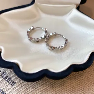 Close-up of elegant silver zircon hoop earrings inside a shell-shaped jewelry box