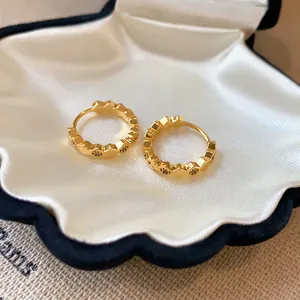 Close-up of elegant 18k gold-plated hoop earrings with zircon stones in a shell box.