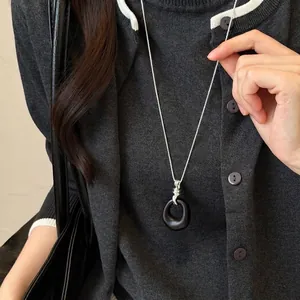 Elegant black round acrylic pendant necklace on silver chain for chic sweater styling