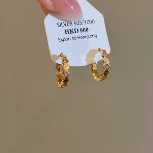 Detail of 18k gold plated hoop earrings with cubic zirconia on a silver 925 tag.