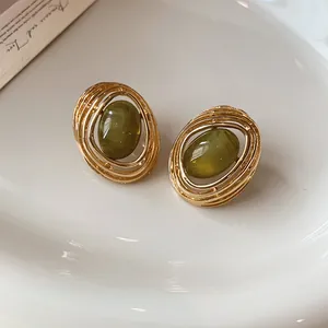 Detailansicht der goldenen ovalen Vintage-Ohrringe mit grünem Harzstein-Inlay.