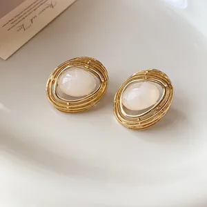Detailaufnahme der Vintage-Ohrstecker in Gold-Ovalform mit weißem Harz-Mittelpunkt