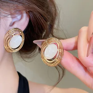 Nahaufnahme von vintage goldenen elliptischen Ohrringen mit weißen Harz-Zentren