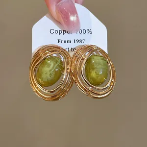 Detail von Vintage-Ohrsteckern aus grünem Harz mit goldenem, hohlem Rahmen