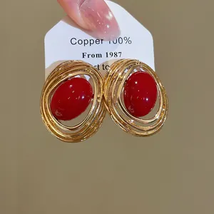 Vintage goldgerahmte ovale rote Harz-Ohrstecker in der Makro-Detailansicht des Designs