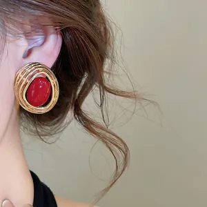 Nahaufnahme eines goldenen ovalen Vintage-Ohrrings mit einem roten Harzstein in der Mitte