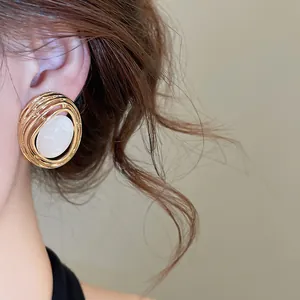 Nahaufnahme von Vintage Gold Hohl Oval Ohrstecker mit elegantem weißem Harzstein Detail