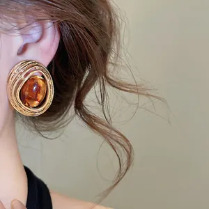 Detailaufnahme von runden Vintage Gold Ohrringen mit elegantem bernsteinfarbenem Harz Steinbesatz