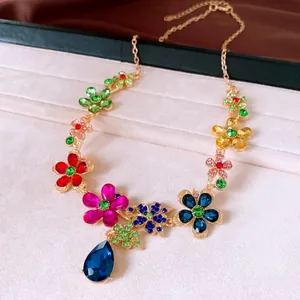 Detailed view of a golden floral necklace with colorful crystals and a blue teardrop pendant