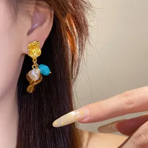 Vintage Maillard style earrings with turquoise and shell charms worn on a model's ear