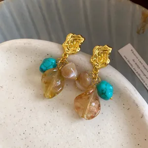 Close-up of vintage Maillard style drop earrings with turquoise and amber leaf beads