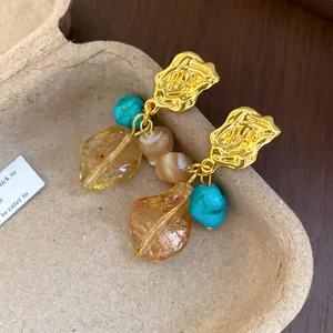 Elegant vintage earrings with turquoise stone and amber resin leaf on gold hammered plate.