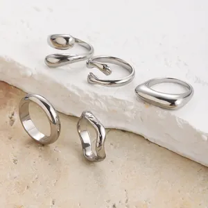 Dettaglio di anelli minimalisti in acciaio inox argento con design geometrico e texture
