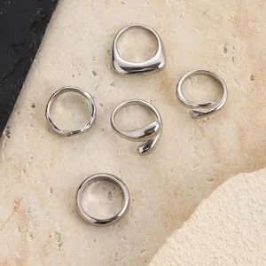 Primo piano di un set di cinque anelli in acciaio inossidabile argento con design diversi.