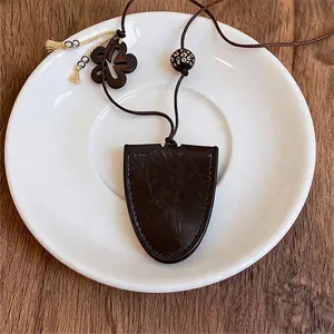 Vintage leren ketting met geometrische hanger en houten bloem op wit schoteltje