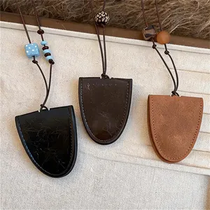 Detailopname van drie retro leren kettingen met geometrische hangers in zwart en bruin