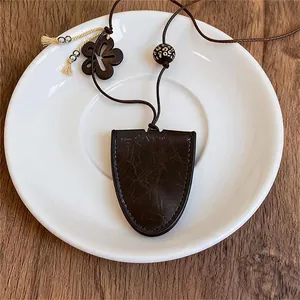 Detailweergave van een vintage ketting met donkerbruin leren schild en houten accenten.