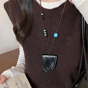 Detailopname van een vintage leren geometrische hanger ketting met kralen gedragen op een trui