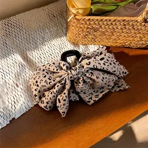 Pinza para el pelo con lazo de tela con estampado de leopardo sobre fondo de madera